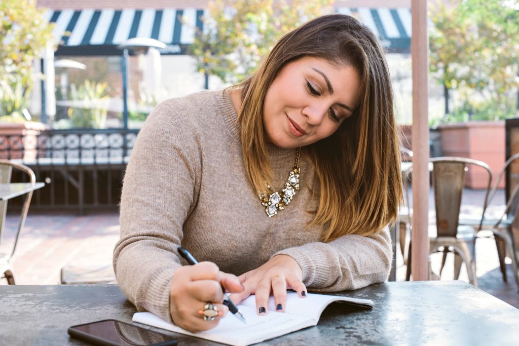 woman writing goals in journal