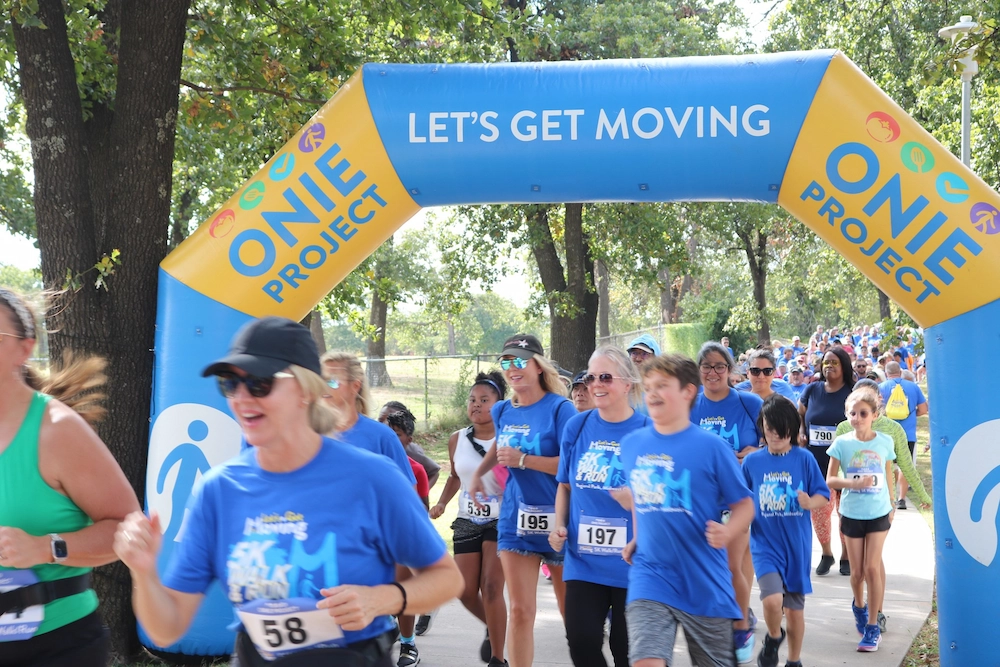 Runners and walkers move under the Let's Get Moving start/finish arch.