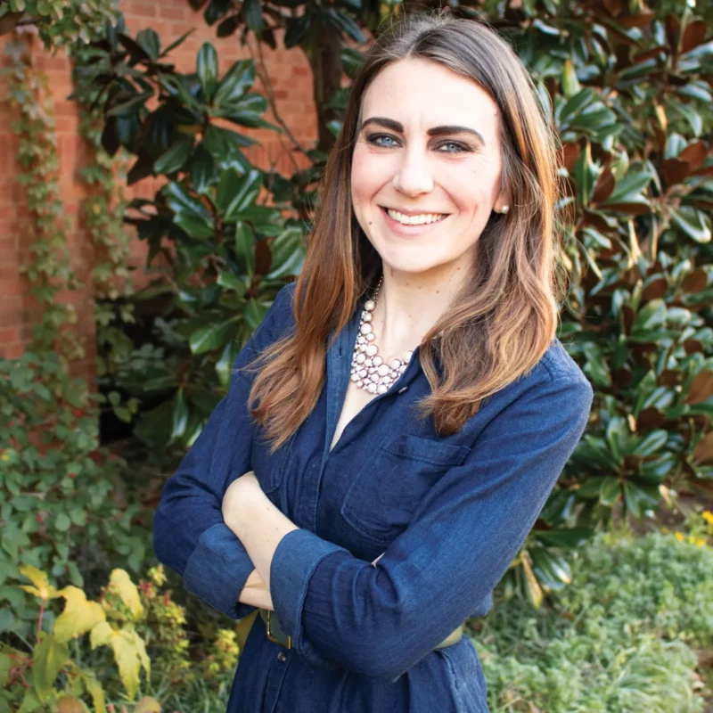 Headshot of Stephanie posing in front of an ivy covered building.