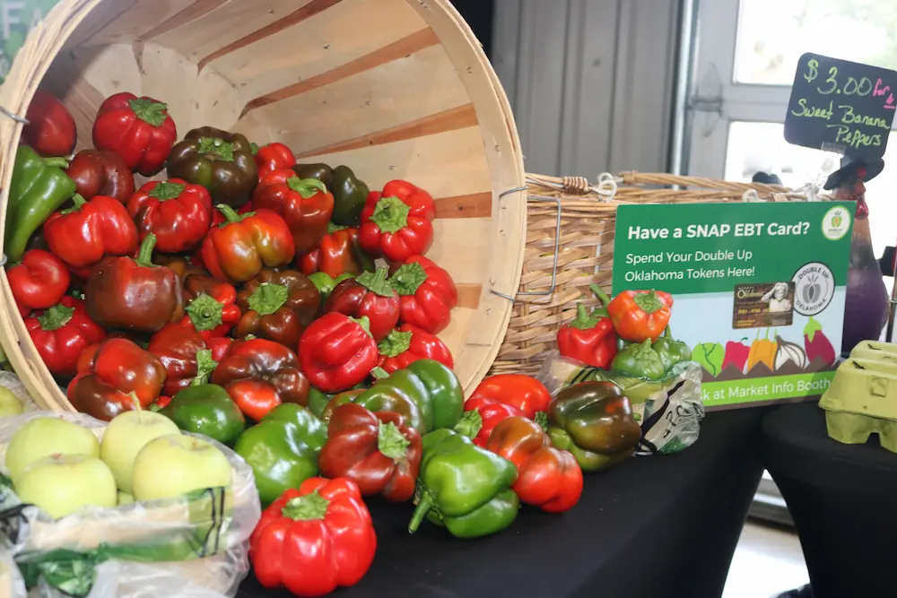 Multi-colored bell peppers spill out of  large basket turned sideways onto the table. A DUO table sign displays in the background.