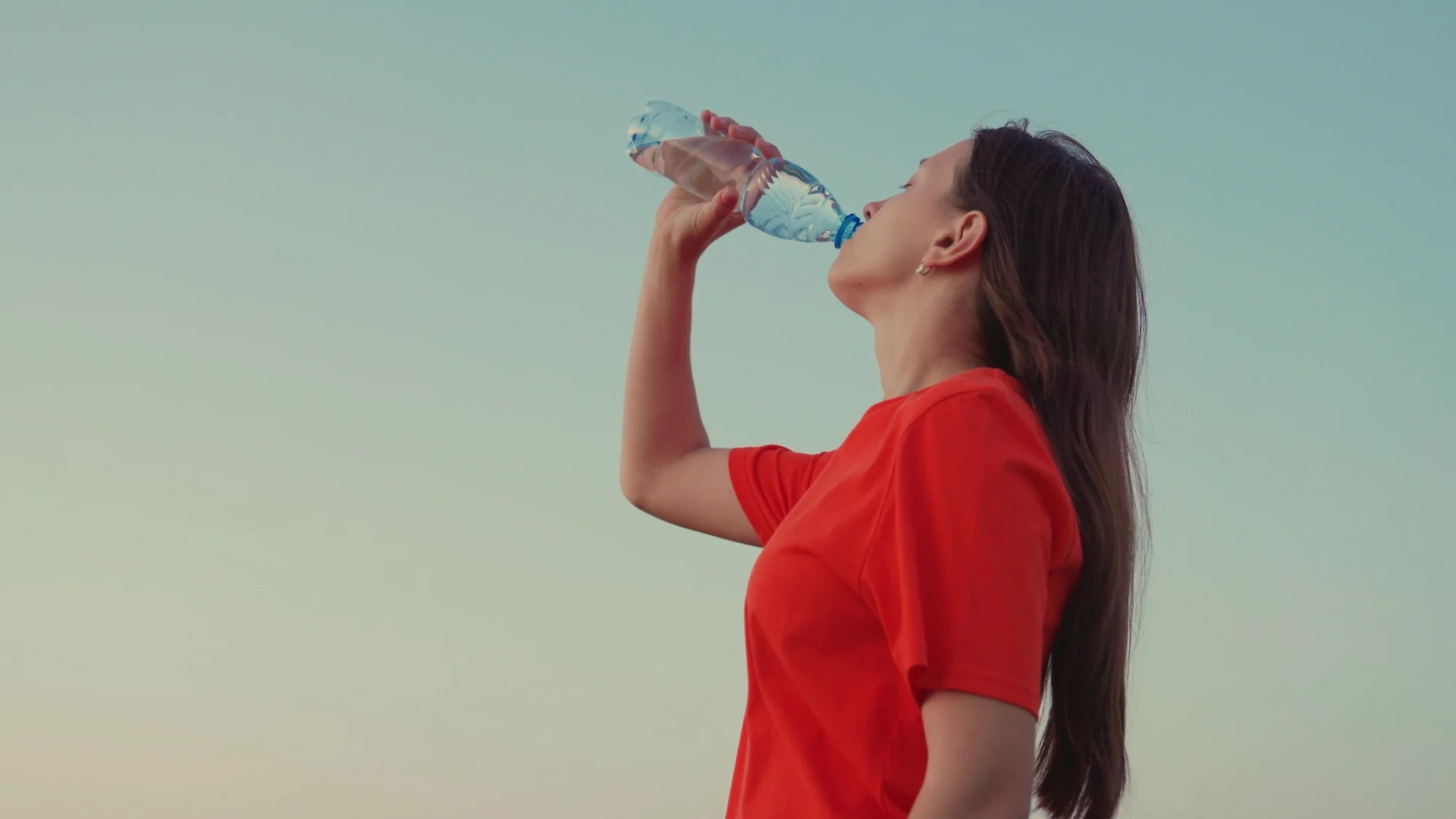 A woman drinks from a bottle of water.