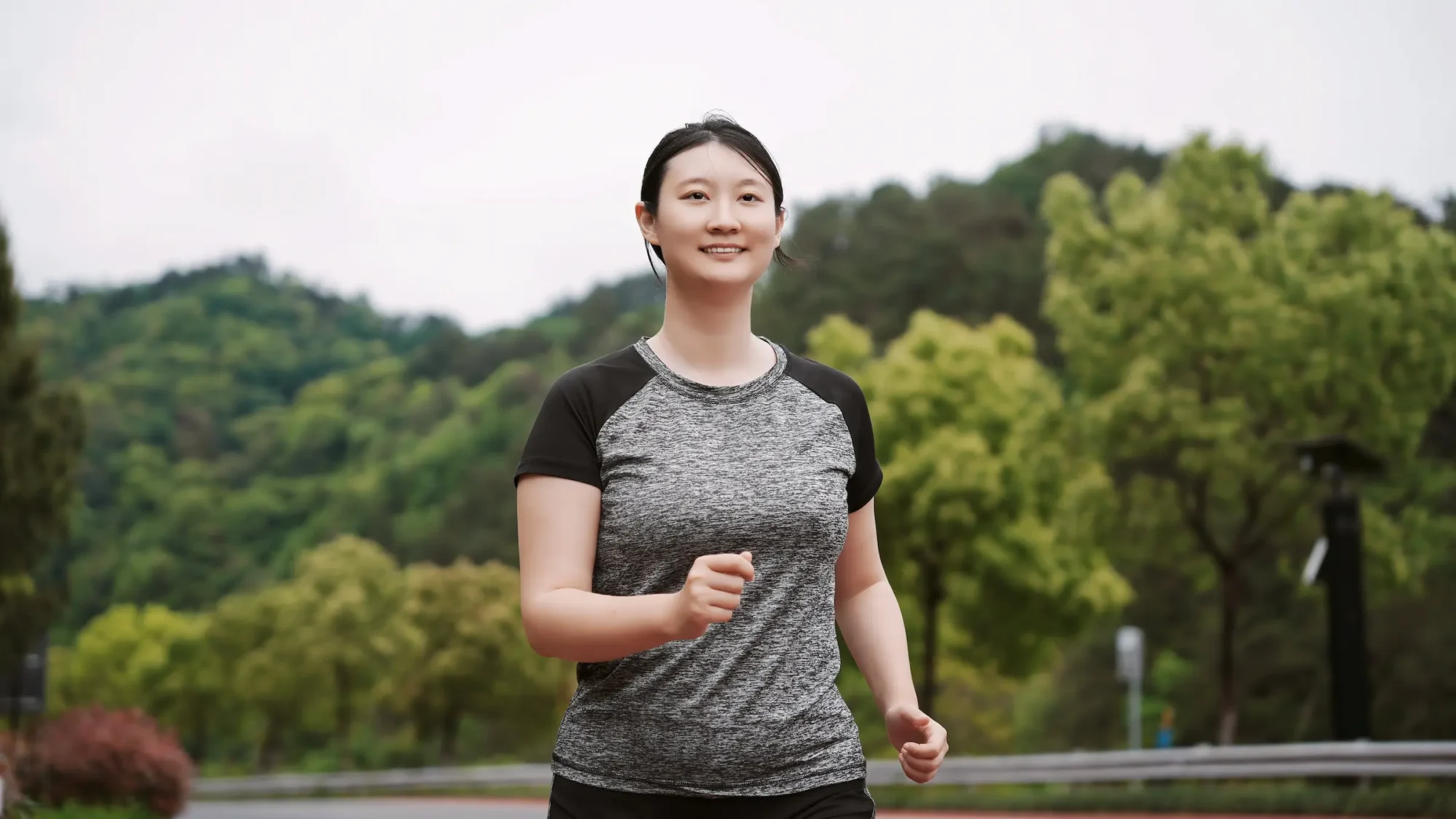 A woman is walking outdoors, appearing upright and relaxed as she walks.